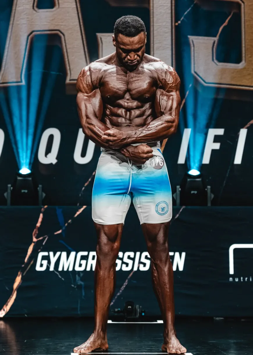 Miles Addison posing on stage at a physique competition